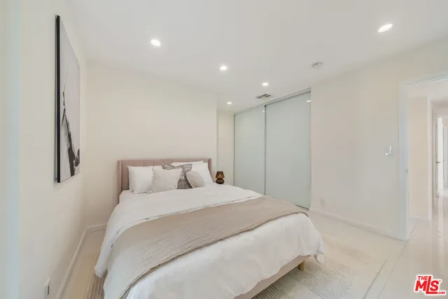 a large bed in a white room with closet