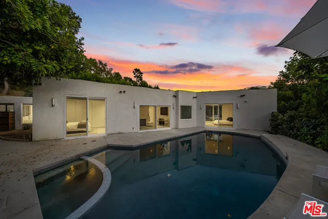 a view of a house with pool fire pit next to a yard