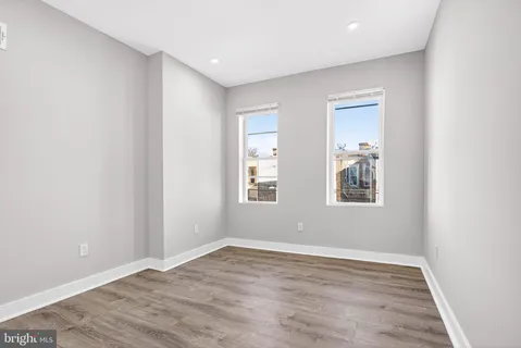 a view of an empty room with wooden floor and closet