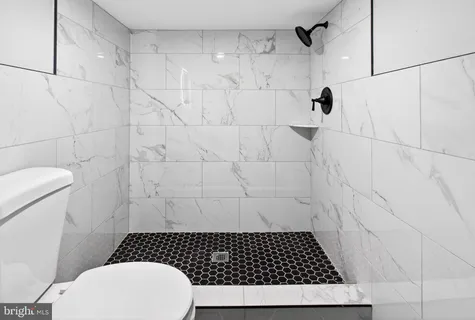 a bathroom with a granite countertop toilet sink and mirror