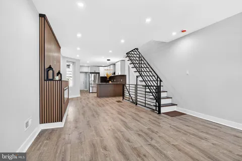 a view of a kitchen with wooden floor electronic appliances and stairs