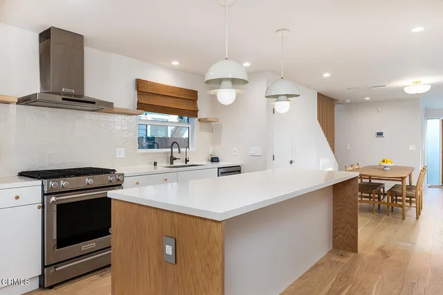 a kitchen with stainless steel appliances a stove sink and wooden floor