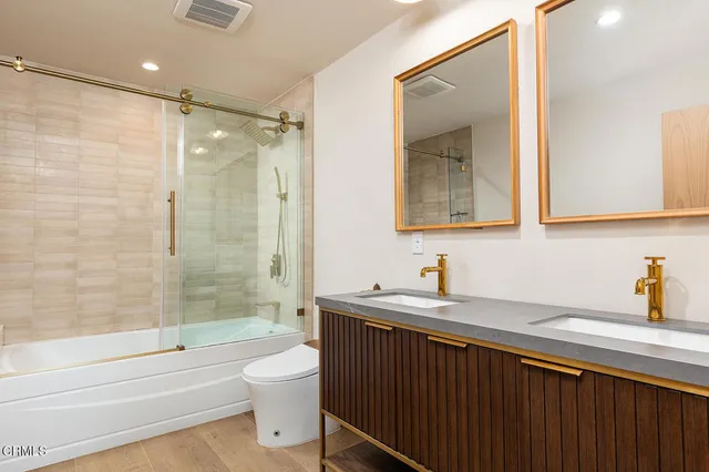 a bathroom with a double vanity sink toilet and shower