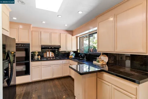 a kitchen with granite countertop a sink a counter top space a refrigerator and cabinets