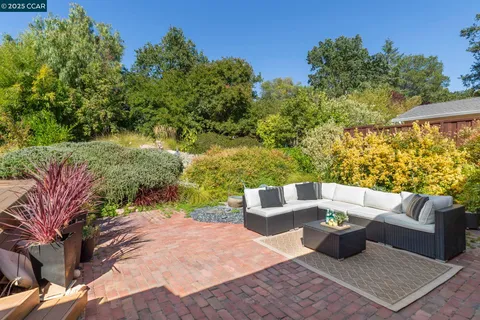 a view of a patio with couches and a table and chairs with wooden floor and fence