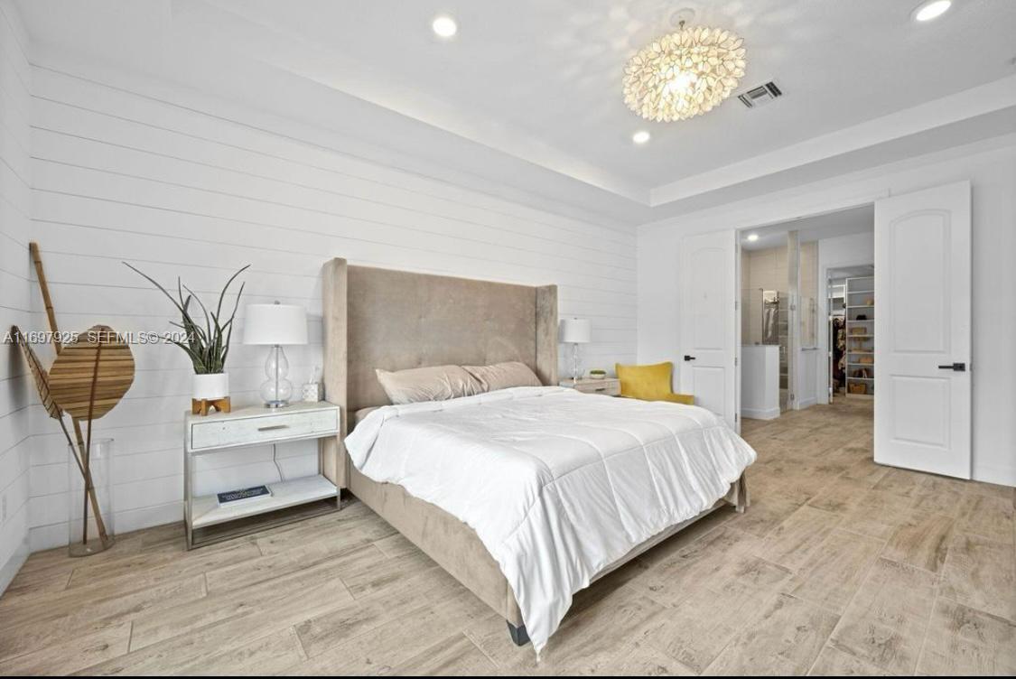 141 Cinder Dunes Point Jupiter, FL 33478 - Photo 15 of 35 a bedroom with a bed and a chandelier