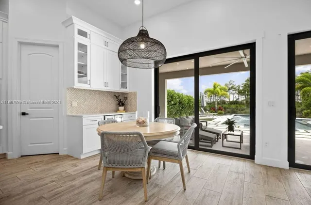 a kitchen with stainless steel appliances a dining table chairs and wooden floor