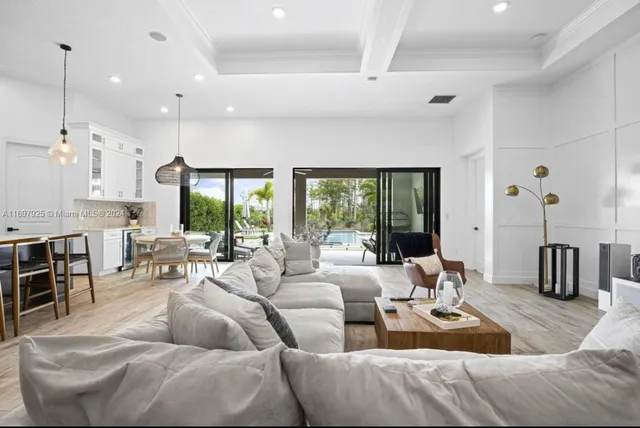 a living room with furniture wooden floor and large windows