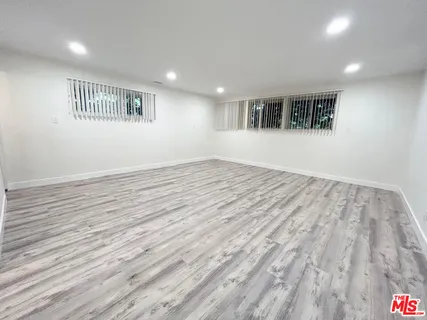 a view of empty room with wooden floor and windows