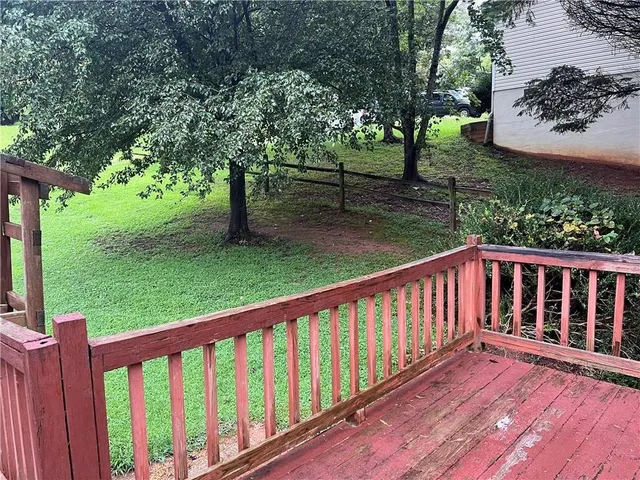 a balcony with wooden floor and yard in the back