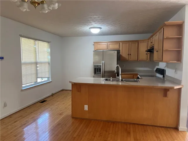 a kitchen with kitchen island granite countertop wooden floors and wide window