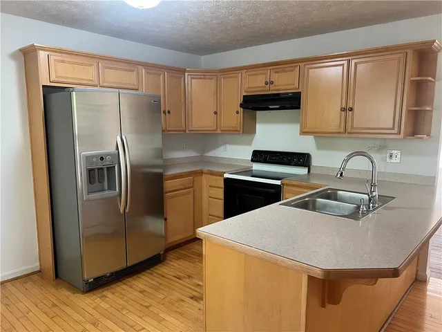 a kitchen with stainless steel appliances granite countertop a refrigerator a sink a stove and island