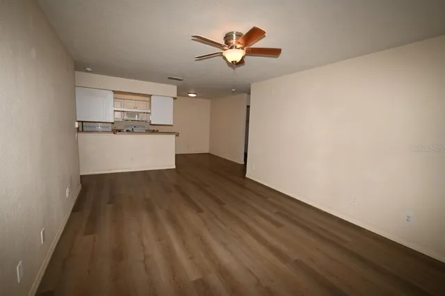 a view of kitchen and empty room with wooden floor