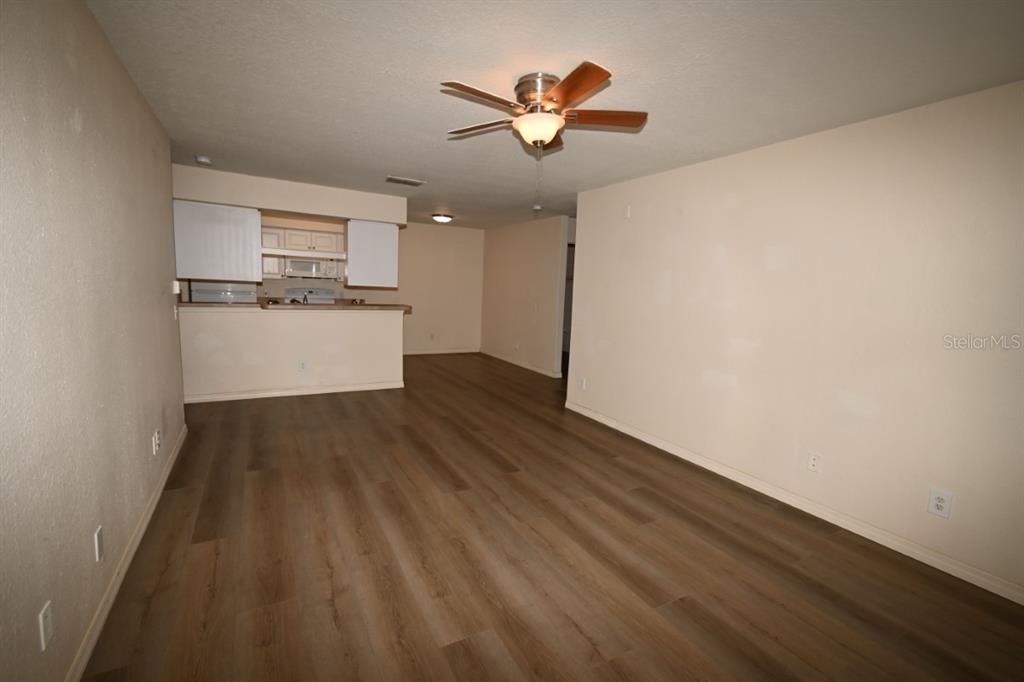 36047 Deer Creek Drive, Unit 102 Zephyrhills, FL 33541 - Photo 5 of 37 a view of kitchen and empty room with wooden floor
