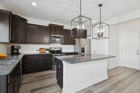 a kitchen with stainless steel appliances granite countertop a sink a stove and a wooden floors