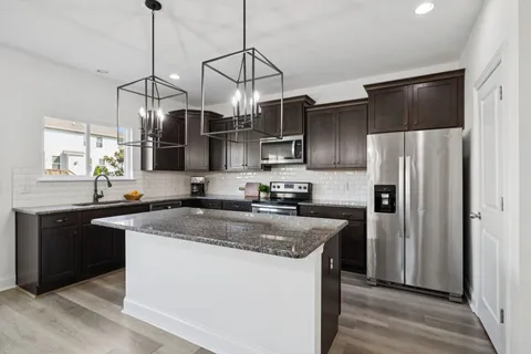 a kitchen with stainless steel appliances granite countertop a sink a stove a refrigerator and island