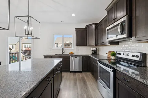 a kitchen with stainless steel appliances granite countertop a sink stove and microwave