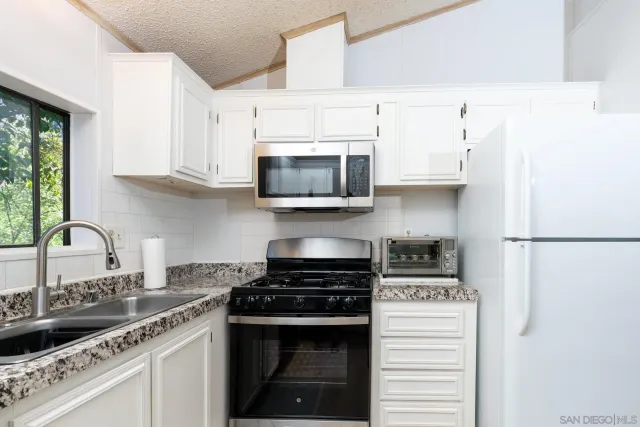 a kitchen with stainless steel appliances granite countertop a stove a sink and a microwave