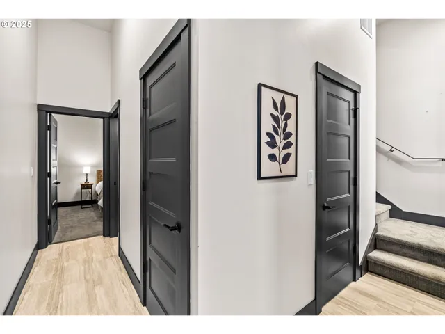 a view of a hallway with wooden floor and a bathroom
