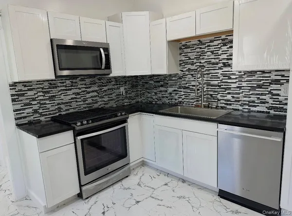 a kitchen with granite countertop white cabinets and stainless steel appliances