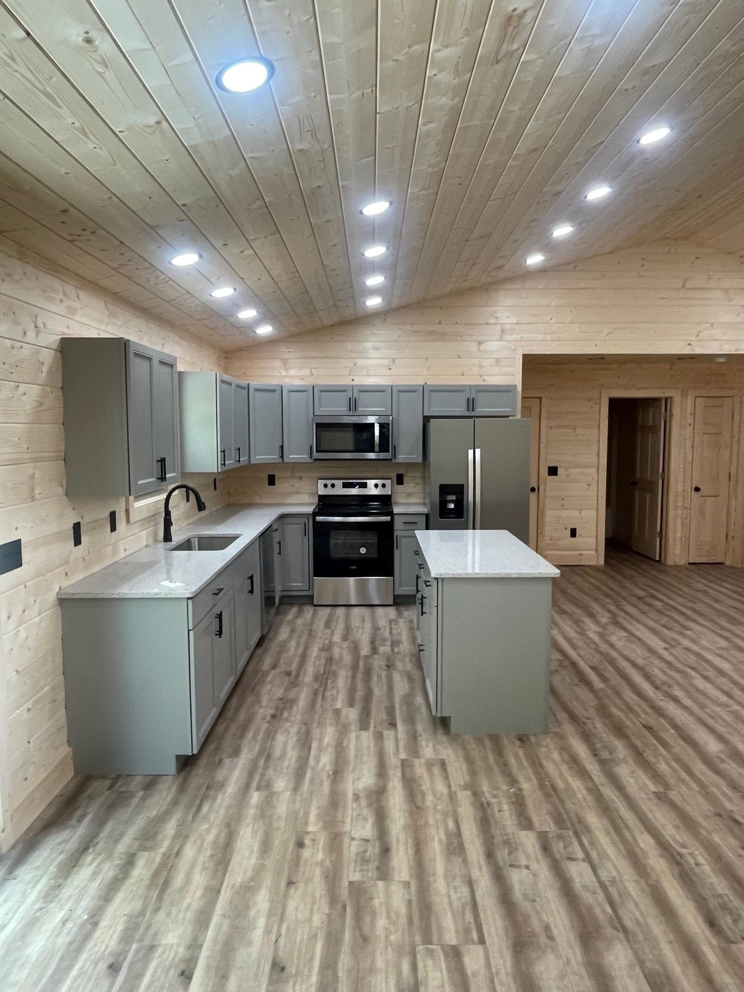60 Trout Pass Mathias, WV 26812 - Photo 12 of 46 a large white kitchen with kitchen island a stove a sink dishwasher and a refrigerator with wooden floor