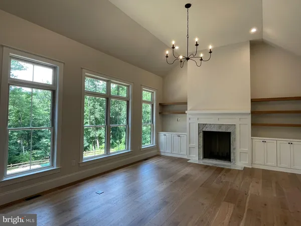 a view of an empty room with wooden floor and a fireplace