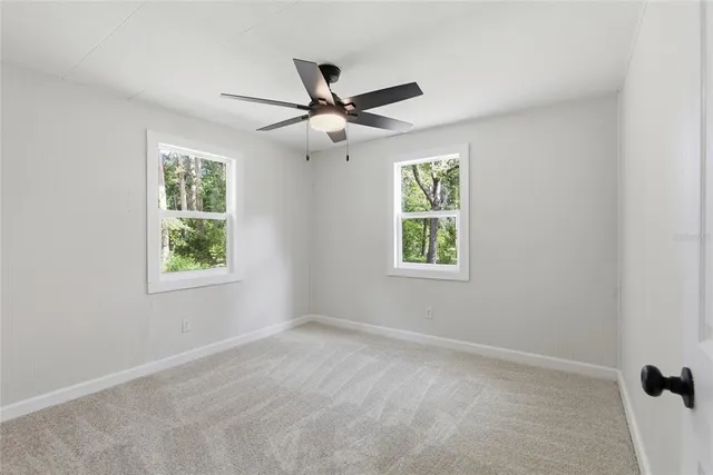 an empty room with windows and fan