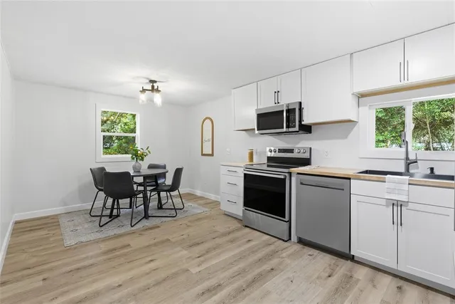 a kitchen with granite countertop a stove top oven a sink dishwasher a dining table and chairs with wooden floor