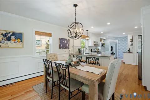 a view of a dining room and livingroom with furniture wooden floor a chandelier