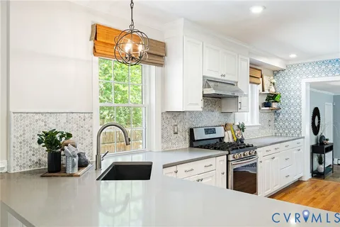 a kitchen with granite countertop a stove a sink and a window