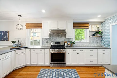 a kitchen with stainless steel appliances a stove a sink dishwasher a refrigerator and white cabinets with wooden floor