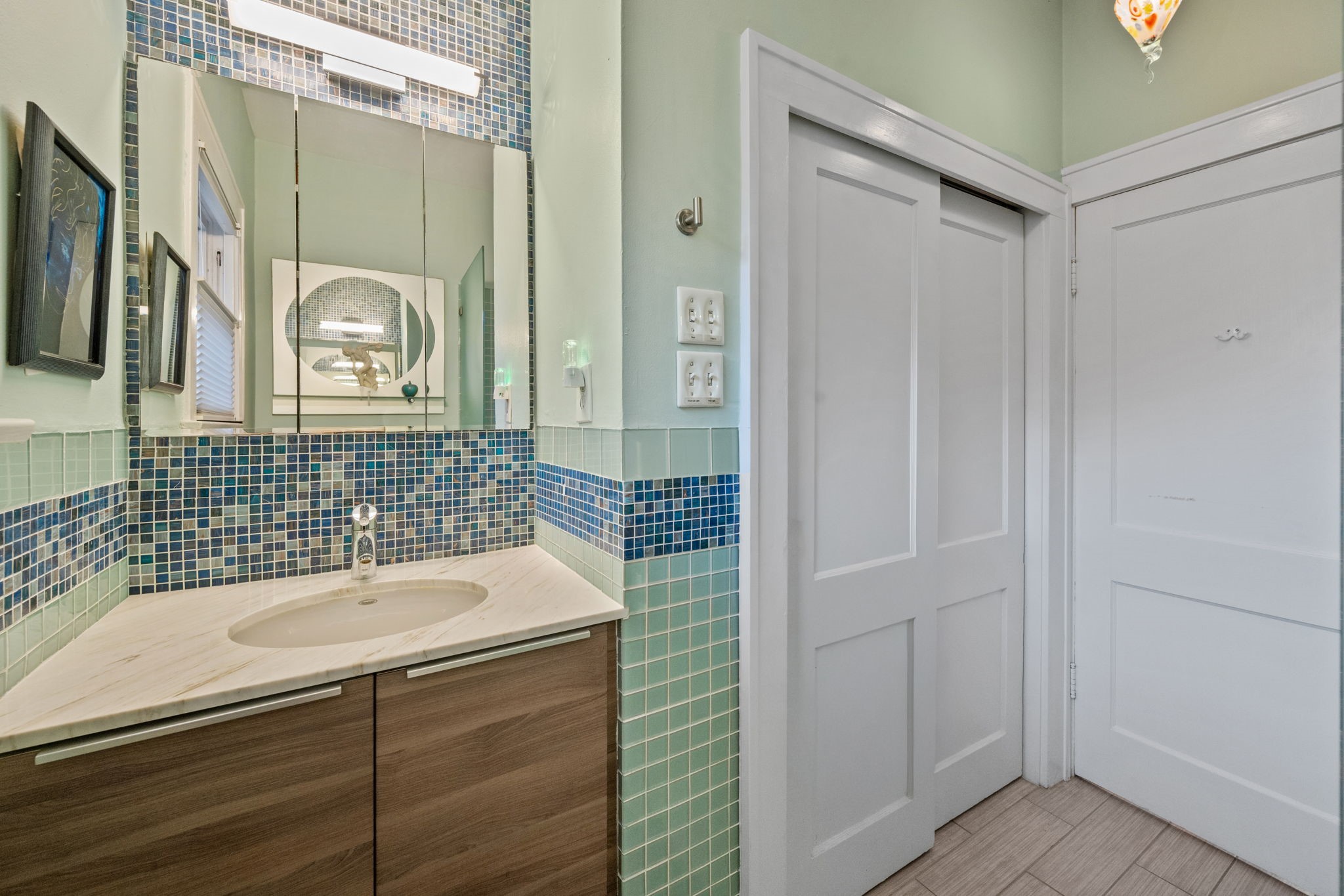 1911 Harold Street Houston, TX 77098 - Photo 13 of 36 Secondary downstairs full bath (7’7” x 8’9”) featuring a frameless glass walk-in shower with artisan tile detailing, a contemporary vanity with stone countertop, a modern overhead light fixture, and a linen closet for additional storage.