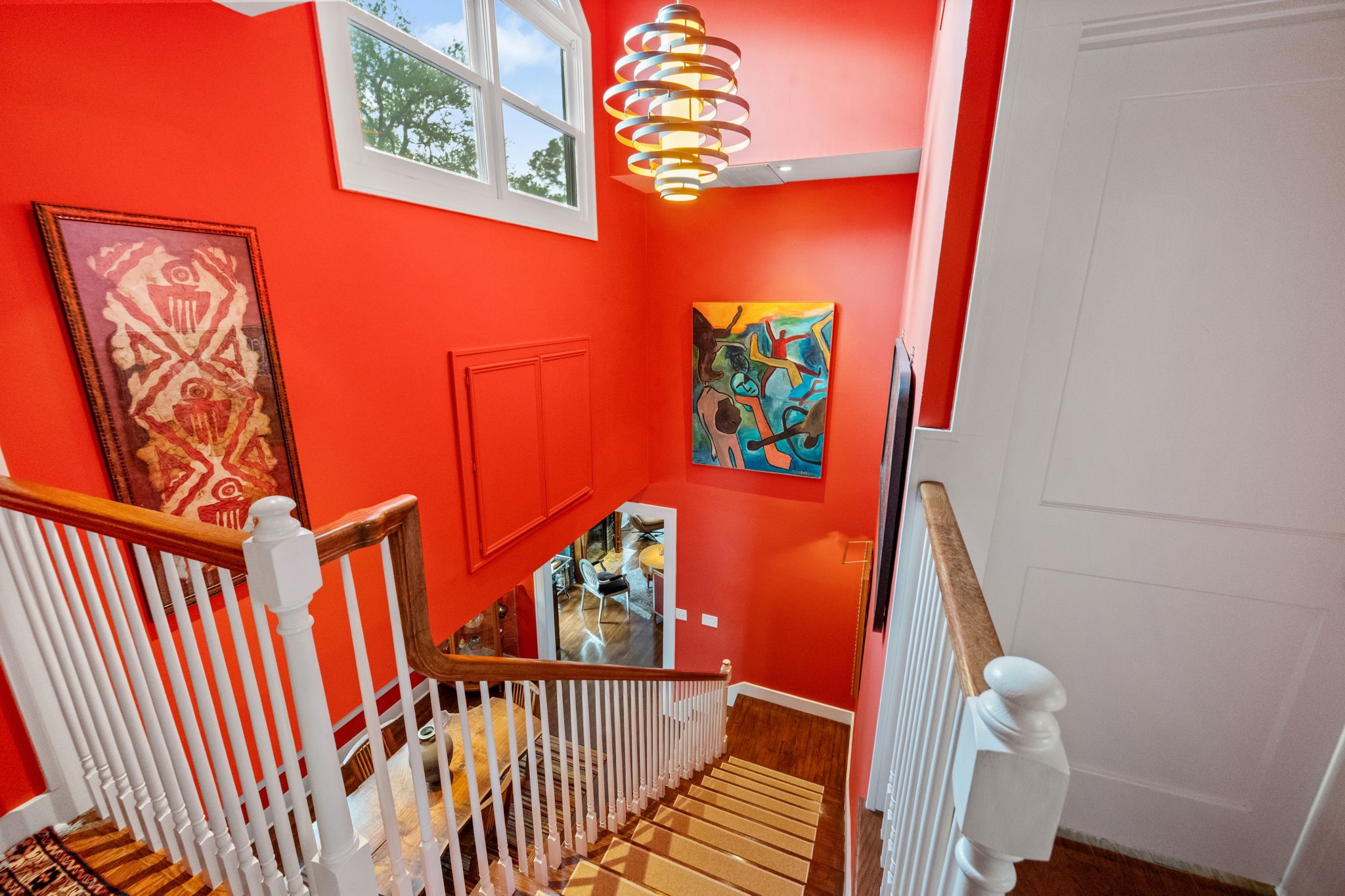 1911 Harold Street Houston, TX 77098 - Photo 16 of 36 View of the staircase from the second-floor landing looking down toward the dining area. The landing features a full wall designed for art display. To the right of the photo is the entry to the primary bedroom, while on the left side of the second-floor landing, a set of French doors opens to the utility closet (not shown).
