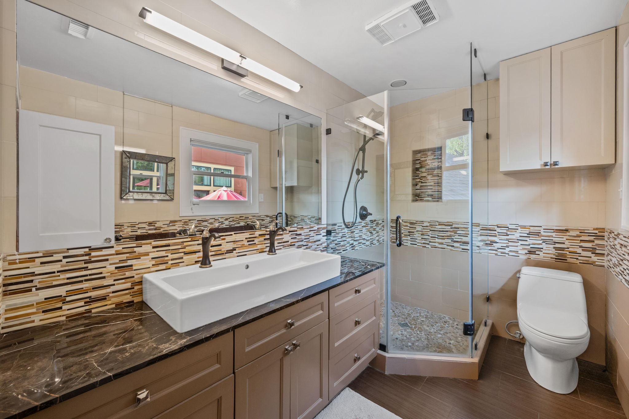 1911 Harold Street Houston, TX 77098 - Photo 20 of 36 Primary bath (10’ x 6’) featuring granite countertops, a frameless glass-enclosed walk-in shower with mosaic tile detailing, and modern finishes. The double vanity includes shaker-style cabinetry, rectangular vessel sinks, dual wall-mounted oil-rubbed bronze faucets, and a medicine cabinet.