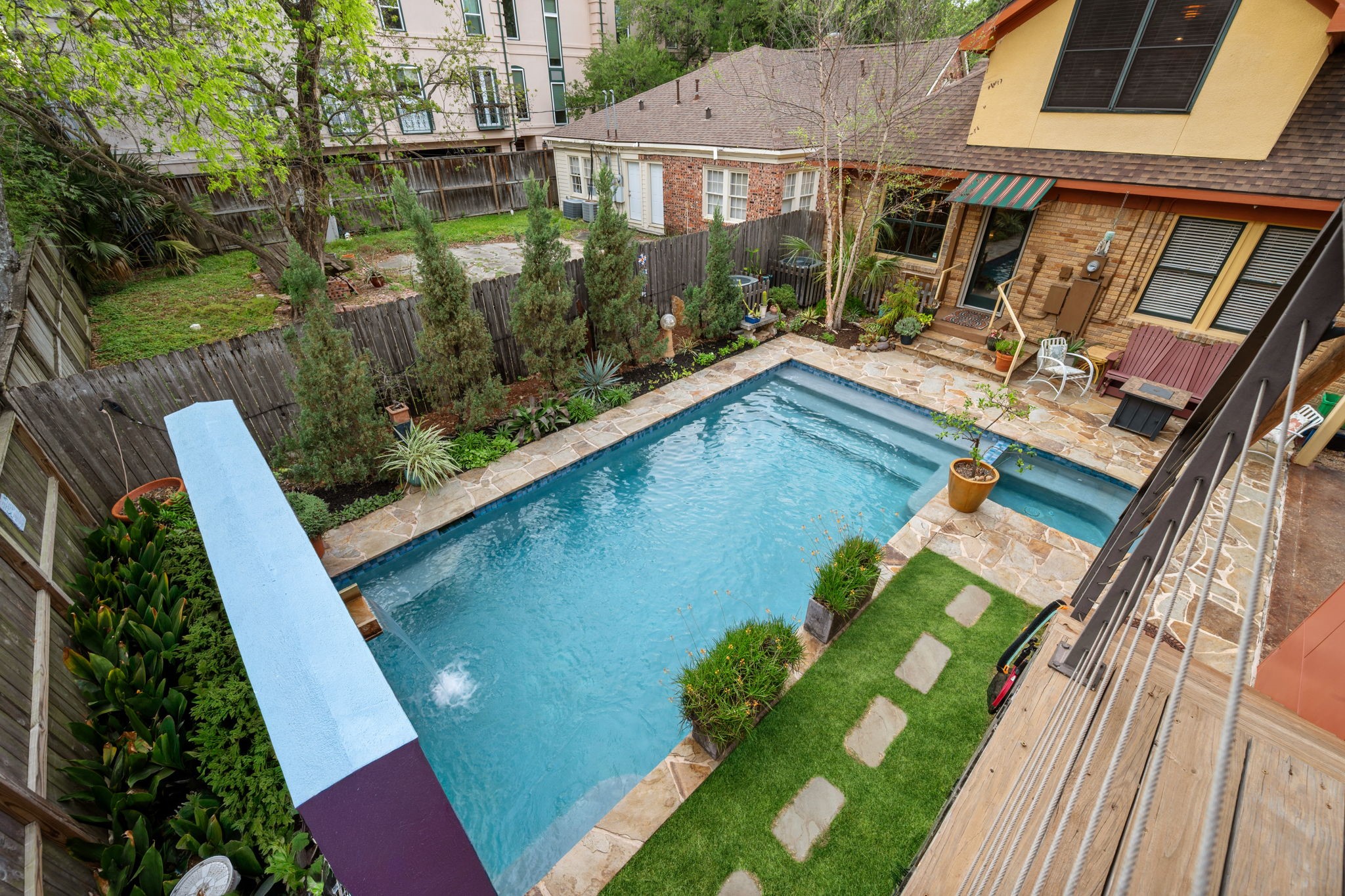 1911 Harold Street Houston, TX 77098 - Photo 27 of 36 The view overlooking the backyard showcases an entertainer’s setting, featuring a heated pool and spa surrounded by lush green space and multiple areas designed for relaxing and gathering.