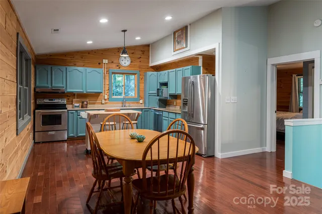 a kitchen with stainless steel appliances granite countertop a dining table chairs refrigerator and sink