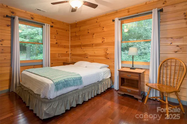 a bedroom with a bed a chair and a large window with wooden floor