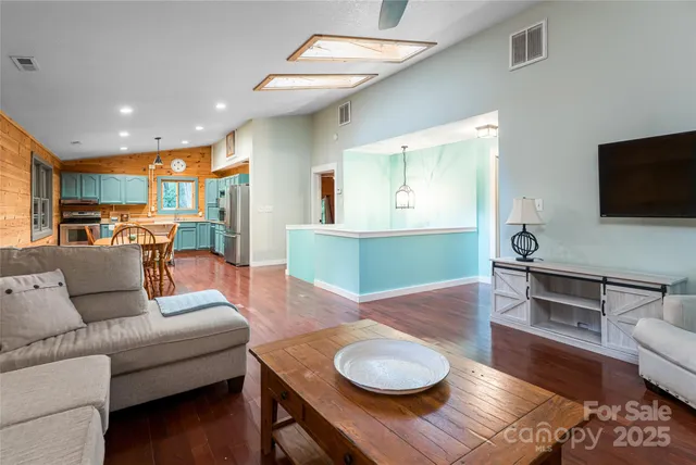 a living room with furniture and a flat screen tv with kitchen view