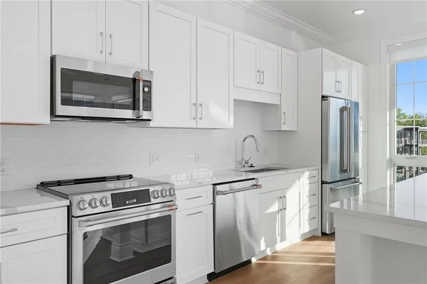 a kitchen with stainless steel appliances granite countertop white cabinets a stove a sink and a white refrigerator with white cabinets