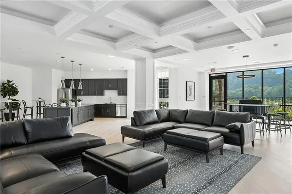 a living room with furniture wooden floor kitchen view and a chandelier