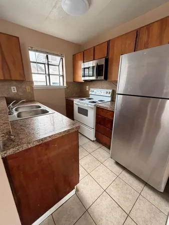 a kitchen with stainless steel appliances granite countertop a refrigerator a stove a sink and a microwave