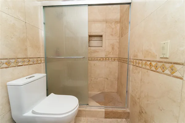 a white toilet sitting next to a shower