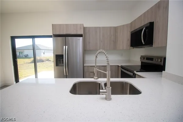 a kitchen with stainless steel appliances a refrigerator a sink a stove and microwave
