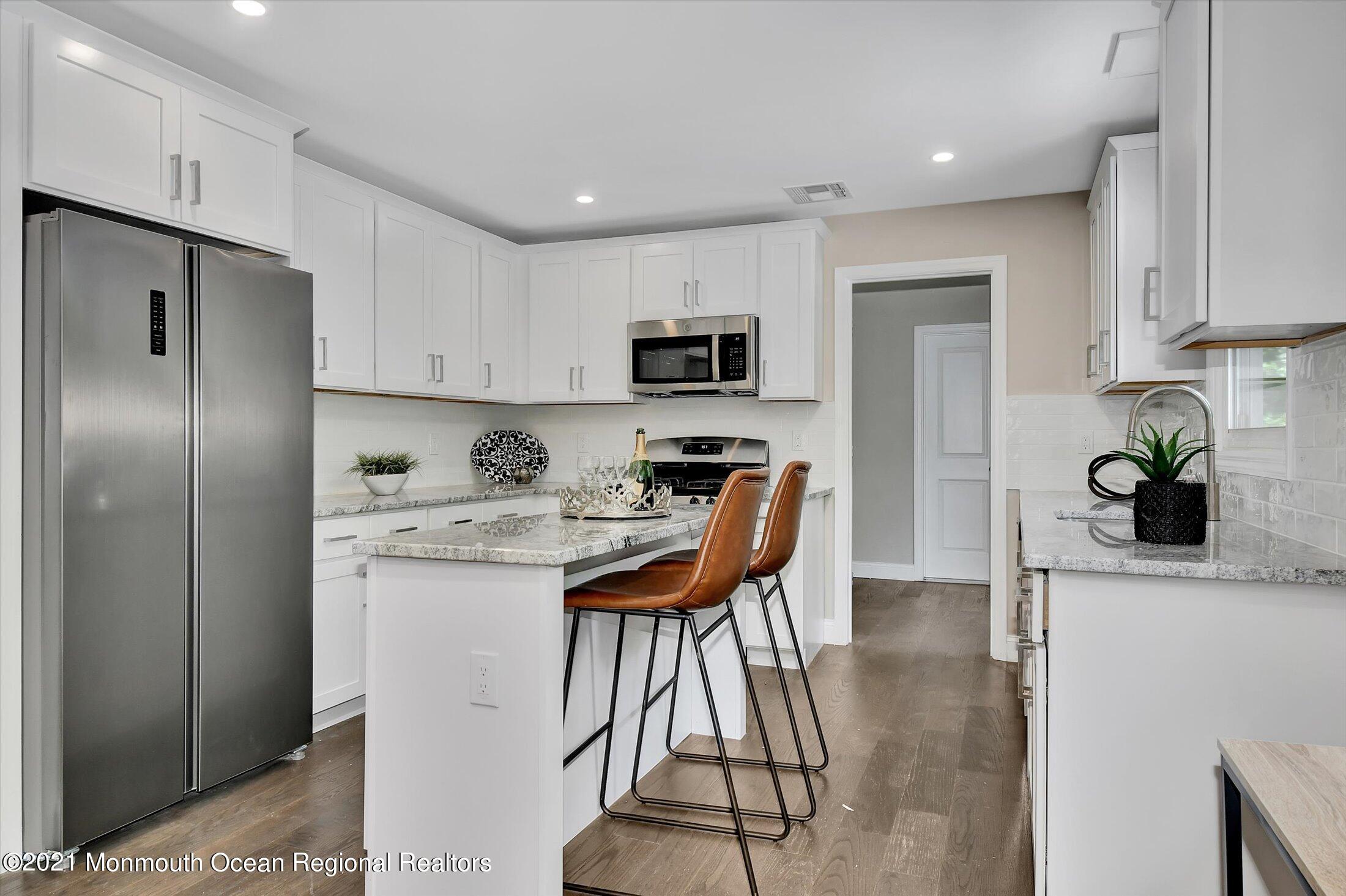 347 Iron Ore Road Manalapan, NJ 07726 - Photo 11 of 27 a kitchen with stainless steel appliances granite countertop a refrigerator a stove a sink dishwasher and a refrigerator with wooden floor