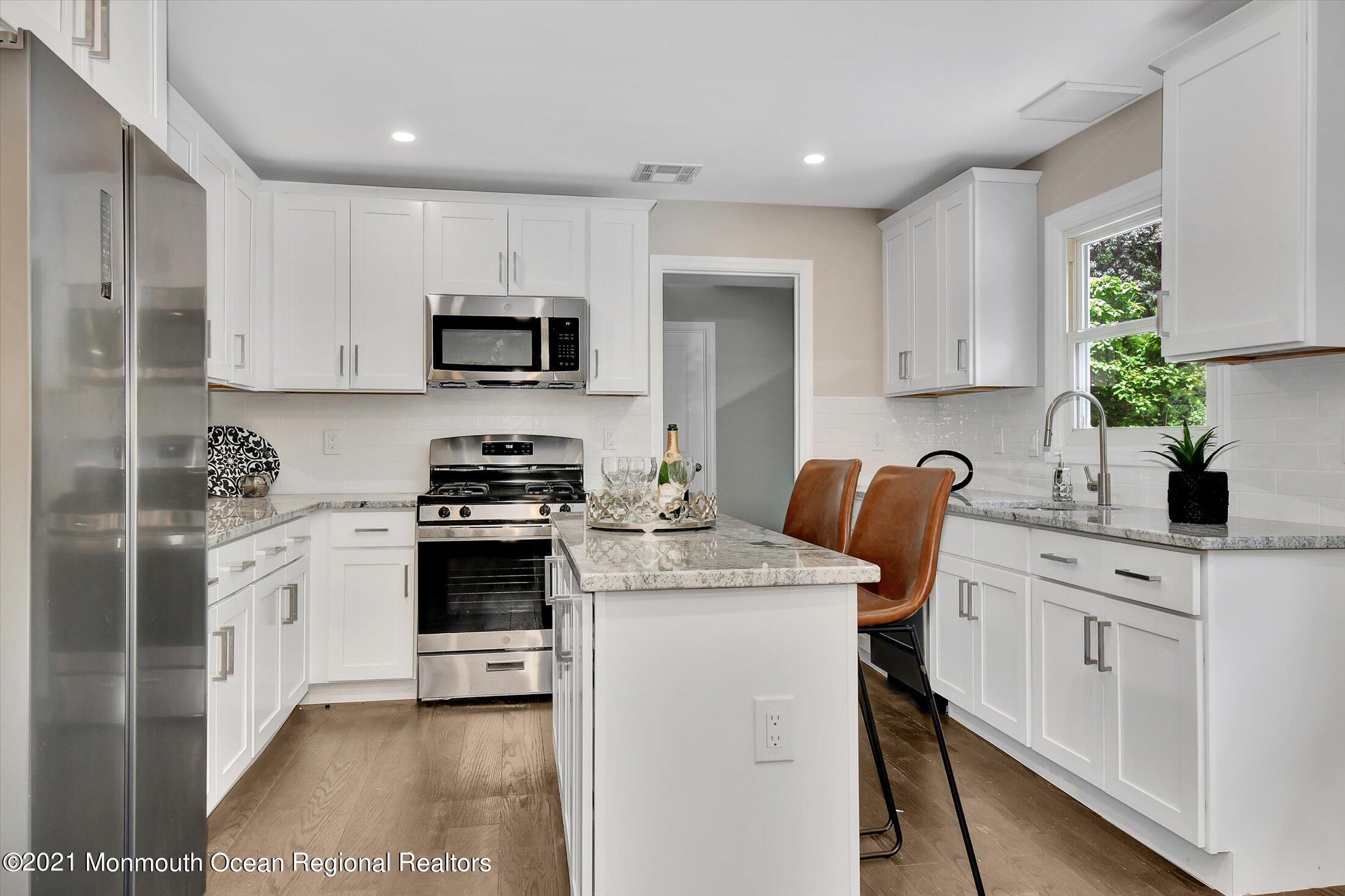 347 Iron Ore Road Manalapan, NJ 07726 - Photo 12 of 27 a kitchen with stainless steel appliances a stove sink microwave and cabinets