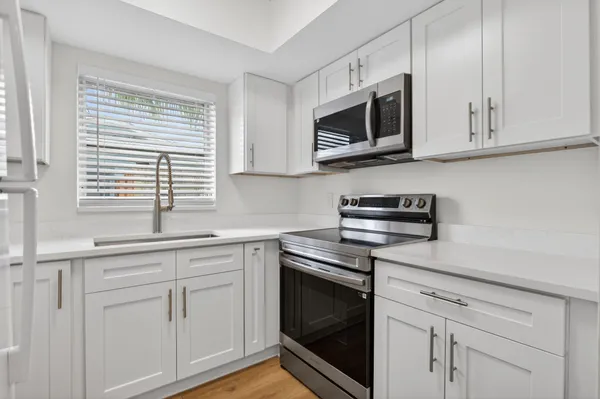 a kitchen with white cabinets stainless steel appliances and sink