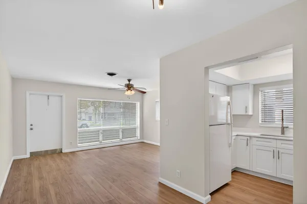 an empty room with wooden floor cabinet and windows