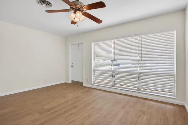 an empty room with windows and fan