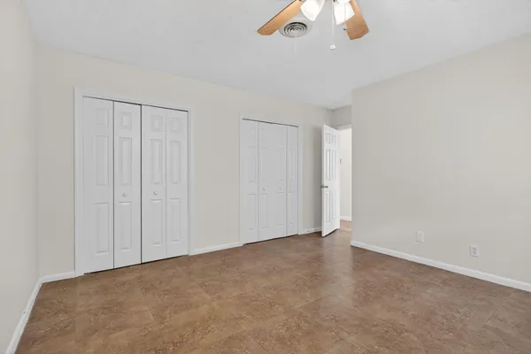 an empty room with a ceiling fan and window