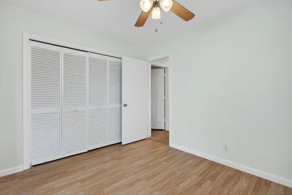an empty room with wooden floor closet and windows